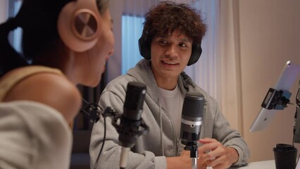 Young happy Asian couple wear headphone sit on desk online live streaming football live score excited cheering watch soccer sport game on laptop talk with audience in small studio at home at night. - Powered by Adobe