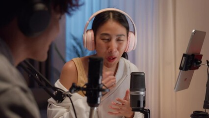 Young happy Asian couple wear headphone sit on desk online live streaming football live score excited cheering watch soccer sport game on laptop talk with audience in small studio at home at night. - Powered by Adobe