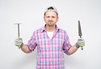 Annoyed male gardener with gardening tools, isolated on white background. Displeased male farmer...