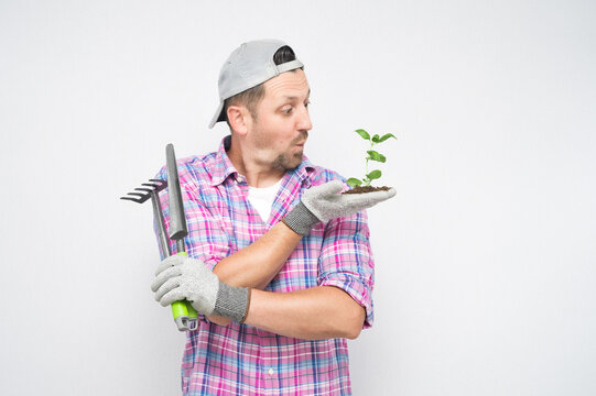 Amazed male gardener with plant and gardening tools, isolated on white background. Amazed male farmer