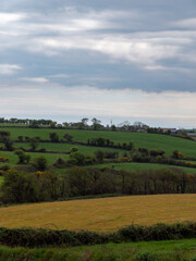Fototapeta na wymiar Picturesque Irish hills under a beautiful cloudy sky. Irish nature, spring landscape. Green grass field under white clouds