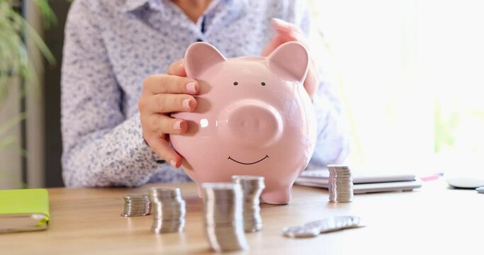A woman in the office strokes a pink piggy bank