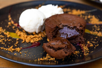 Plate of delicious warm dessert chocolate cake Fondant served with ice-cream balls. Lava cake on a decorated plate.