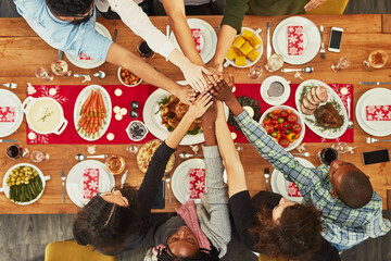 Christmas, high five and food with a group of friends sitting around a dinner table together for...