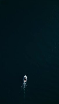 Drone following a small white boat in dark sea