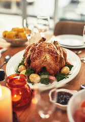 Thanksgiving, food and celebration with a turkey serving on a table in a home for tradition in the holidays. Christmas, chicken and eating with a meal served on a wooden surface from above for dining
