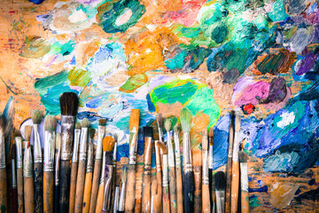 Row artists of Paintbrushes with different sizes lying on the dirty artistic palettes with free space on top,background for creative art design (workspace), close, horizontal image