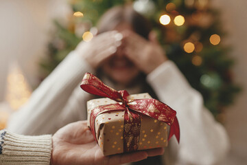 Merry Christmas and Happy Holidays! Hand holding christmas gift box on background of happy woman...