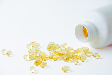 Close-up of plastic bottle with yellow evening primrose oil pills on a white background, horizontal