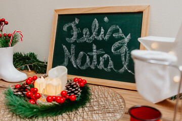 Table with Christmas decor. On the green board merry christmas is written in portuguese. Ceramic...