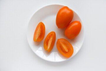 Yellow ripe tomatoes on a plate on a white background. Tomatoes close-up.