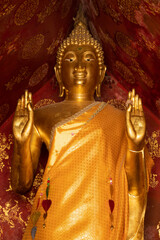 Golden statue of a standing Buddha performing the abhayamudra gesture at Wat Xieng Thong temple in Luang Prabang, Laos