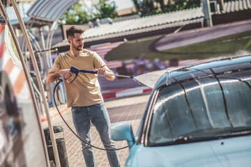 Experienced car detailer washing a customer vehicle outdoors