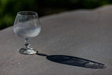 empty glass vase on stone surface with its shadow and reflection by the effect of sunlight.
