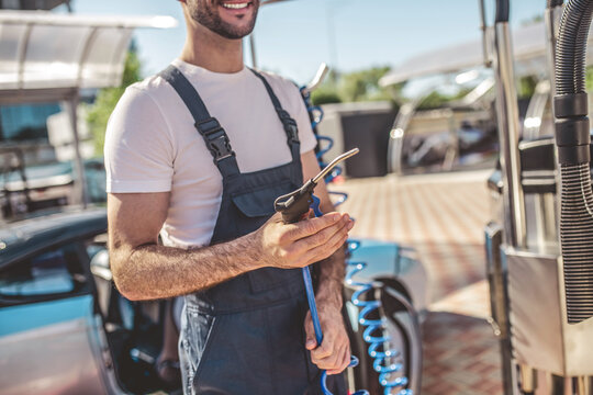Cheerful service station worker preparing for a client car washing procedure