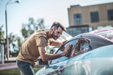Auto detailer cleaning the exterior of a client motor vehicle