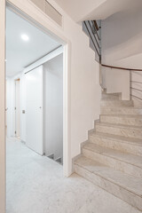 Spiral stairway with white stairs and railing on wall inside of modern apartment with corridor.