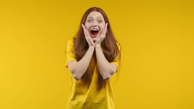 Shocked woman with ginger hair very glad, she screaming loud WOW. Lady trying to get attention. Concept of black friday sales, profitable offer. Excited happy girl on yellow background.