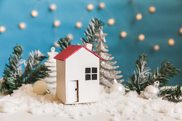 Fototapeta na wymiar Abstract Advent Christmas Background. Toy model house and winter decorations ornaments on blue background with snow. Christmas with family at home concept