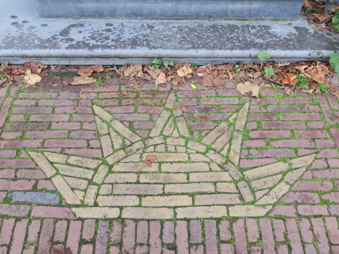 image of the sun in two colored bricks om the sidewalk in front of a house