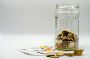 British Currency pound coins, receipts and loyalty cards. Money in a jar, counting the cost   of...