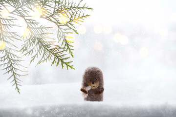 Cute little hedgehog on snowy winter background, christmas tree branches, snowflakes, snow, blurred background. Hedgehog in fog. New Year or Christmas holidays background, copy space