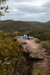 Obraz premium Ein Paar genießt nach der Wanderung, vom Gipfel des Berges, die atemberaubende Aussicht der Landschaft mit einem wunderschönen Sonnenuntergang