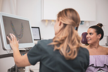 The female doctor shows the results of the digital intraoral scan of the patient's teeth in 3D on...