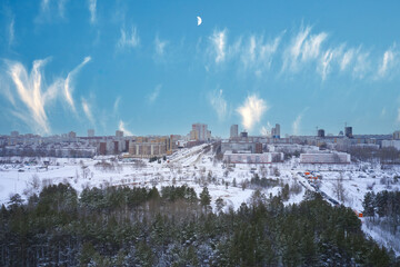Obraz premium Aerial view of a winter city with skyscrapers, snow-covered streets and a park area. Shooting from a drone.
