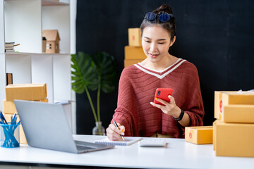 Portrait of an Asian businesswoman using a telephone to contact customers. online products to sell products and take orders for delivery of packages.