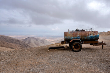 Rusty water tanker truck placed on the side of the gravel road in the desert, near Jericho city. West Bank