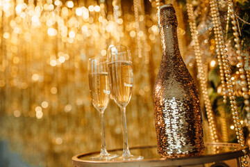 Champagne bottle and glasses against luxury glow golden rain decoration expensive holidays party