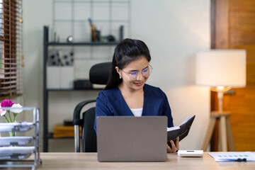 Portrait of a beautiful and attractive Asian businesswoman smiling and taking notes. Guidelines for doing business, finance, and marketing.