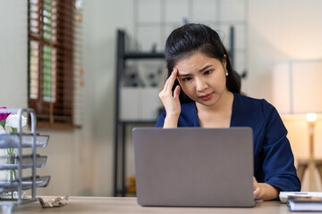 A portrait of an Asian businesswoman stressed and aching with her work in the office along with the idea of ​​management. documents on her desk.
