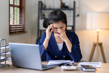 A portrait of an Asian businesswoman stressed and aching with her work in the office along with the idea of ​​management. documents on her desk.