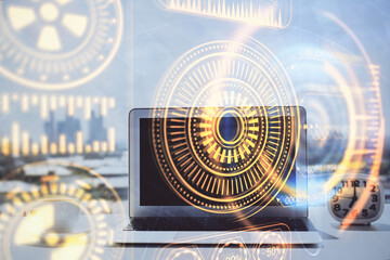 Computer on desktop in office with technology theme hologram. Double exposure. Tech concept.