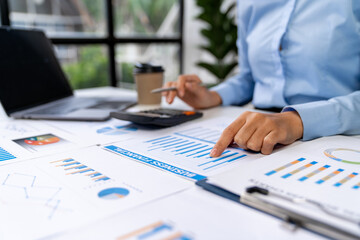 Asian business ideas are thinking and calculating with a calculator. front view of hand pointing to business data chart to calculate analysis Company financial processing.