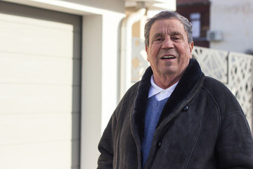 Fototapeta premium Cheerful senior man in front of house