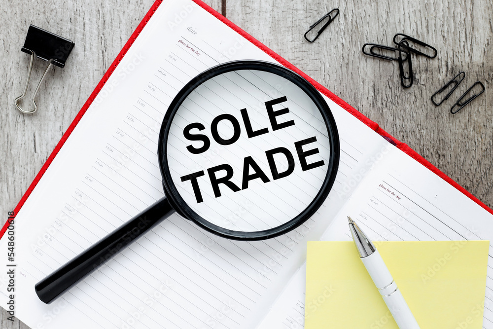 Poster sole trader text on magnifier glass. on the work table