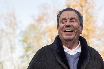 A smiling and satisfied elderly man walking through the park