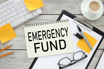 EMERGENCY FUND : Concept of setting money saving goal for rainy day. text on paper on black folder. near the white keyboard