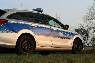 Radiowóz polska policja wieczorem z sygnalizatorem błyskowy niebieski na dachu. Nocny patrol.