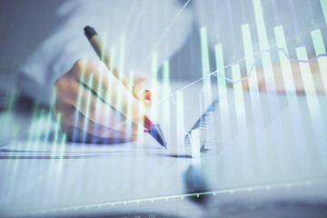 Double exposure of woman's hands making notes with forex graph hologram. Concept stock market analysis.