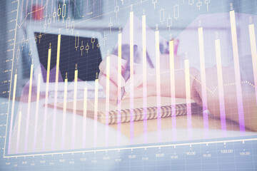 Financial graph displayed on woman's hand taking notes background. Concept of research. Double exposure