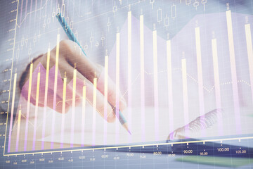 Financial forex graph displayed on hands taking notes background. Concept of research. Double exposure