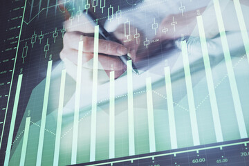 Financial forex graph displayed on hands taking notes background. Concept of research. Double exposure