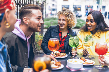 Multiracial friends drinking cocktails and having fun together at bar outdoors - Young people leisure concept 