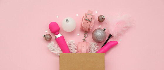 Box with different sex toys and Christmas decor on pink background