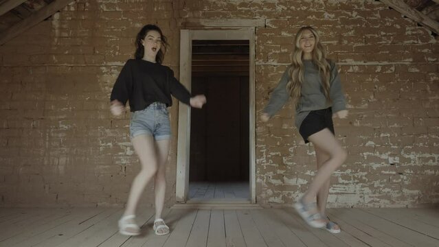 Teenage girls performing dance routine in empty attic / Grafton, Utah, United States