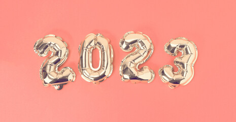 New Year 2023. Foil balloons numbers 2023 on a pink background. New Year Christmas.